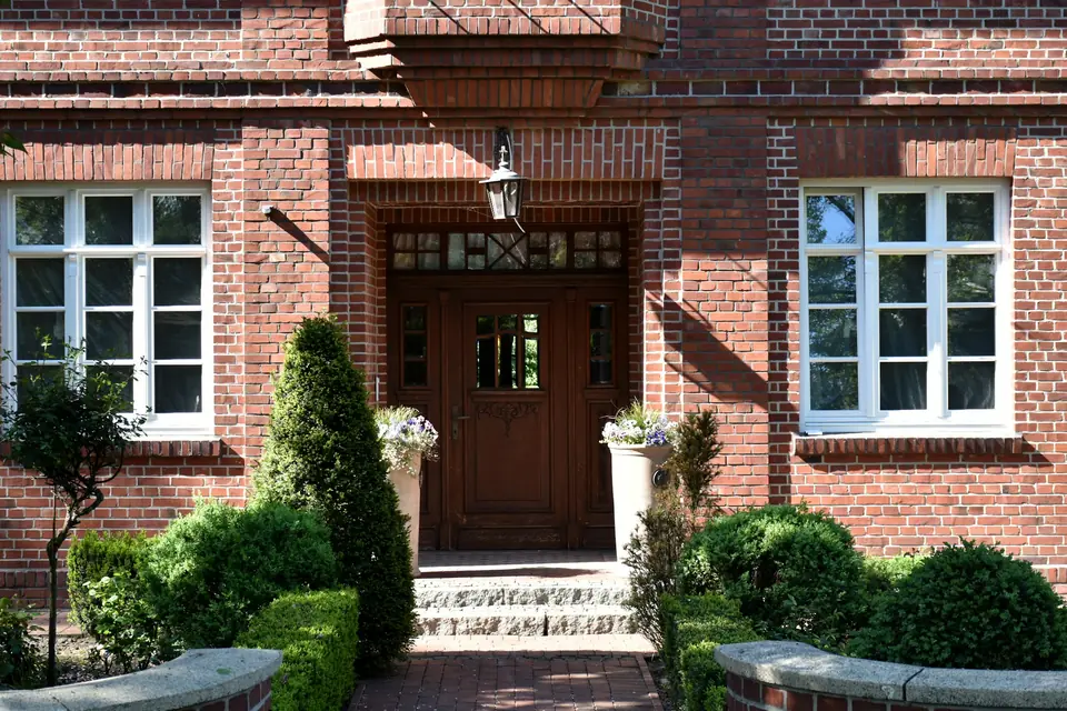 Eingang eines gepflegten Backsteinhauses mit Grünanlage